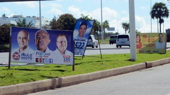 Nas ruas, calçadas, praças, inclusive, postes de iluminação pública, sinalização de tráfego, viadutos, passarelas, pontes, paradas de