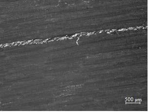 a b Figura 3 - Região lateral da amostra de PPS/fibra de carbono soldado condicionado na câmara UV (10X).