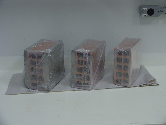 A Figura 10 mostra os tijolos revestidos com filme plástico de PVC, tanto para evitar que a argila absorvesse água quanto para vedação dos furos do tijolo, pois a densidade efetiva considera a