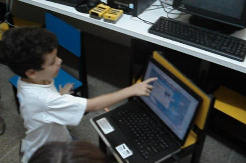 Figuras V e VI: Figura V, monitora ministrando conteúdo de informática às crianças. Figura VI, um dos integrantes do projeto, durante a realização da oficina de robótica pedagógica.