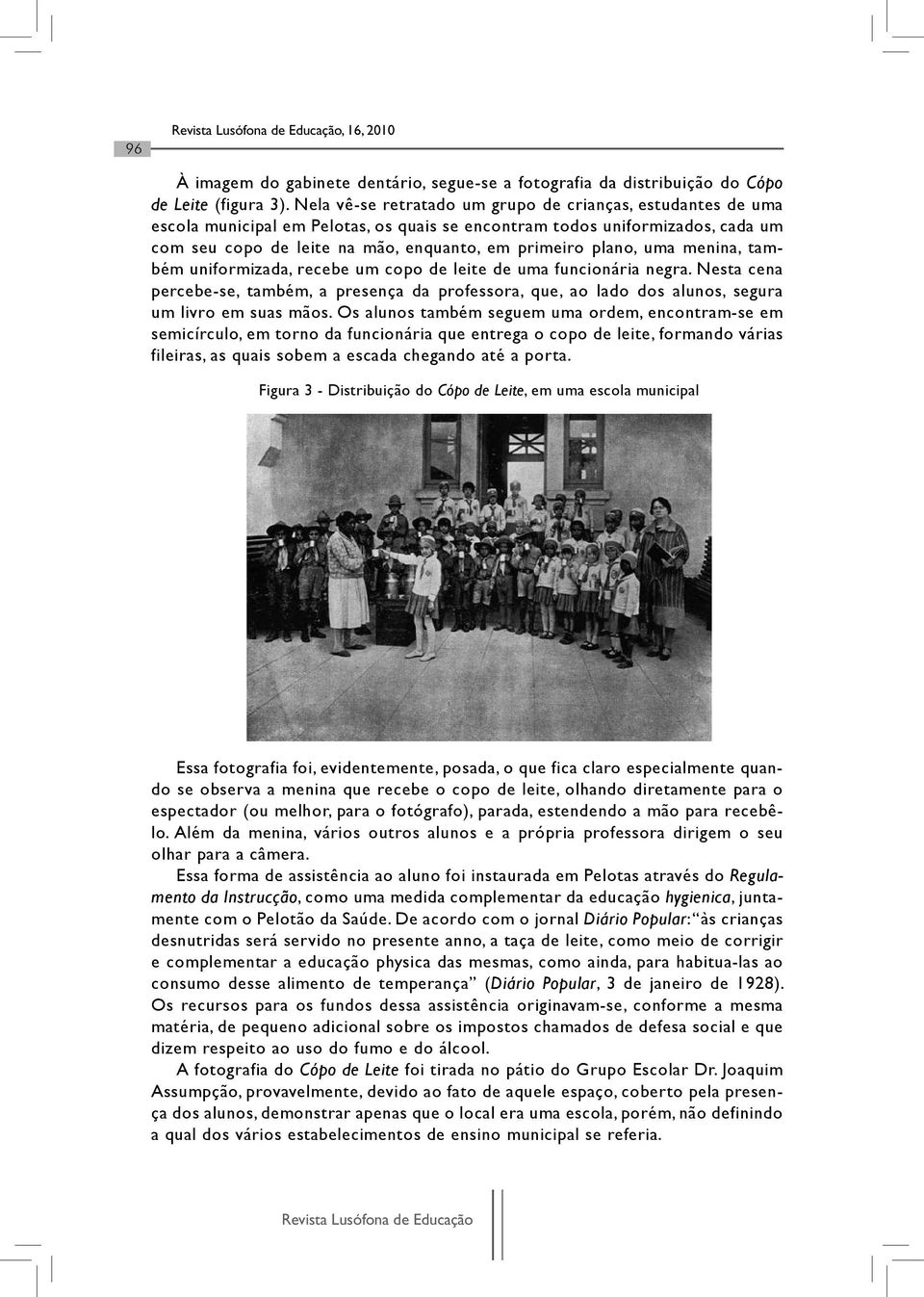 uma menina, também uniformizada, recebe um copo de leite de uma funcionária negra. Nesta cena percebe-se, também, a presença da professora, que, ao lado dos alunos, segura um livro em suas mãos.