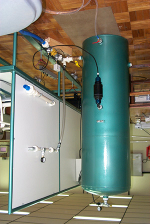 A figura 4 apresenta uma vista de fundo da bancada apresentando em primeiro plano o tanque hidropneumático com carregador de ar e as conexões hidráulicas que ligam o tanque à bancada.