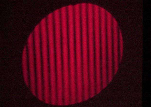 Interferência de Ondas Planas Figura 5 Foto da montagem experimental, mostrando o laser e o divisor de feixes (ao fundo), a escala micrométrica e a lente (no centro da bancada), o anteparo