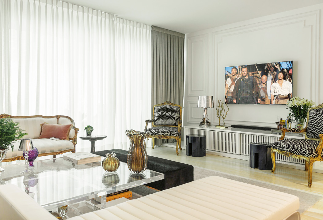 O sofá modelo Luiz XV tem entalhes artesanais, acabamento de laca na cor ouro-antigo e estofado listrado com suave brilho perolado.