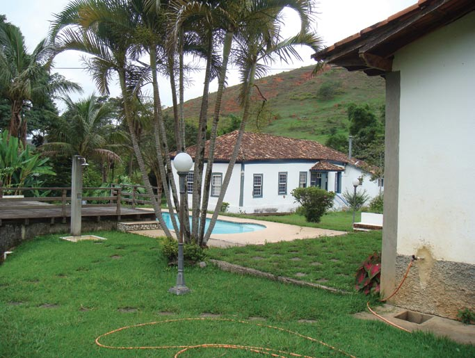 situação e ambiência Próximo à casa, um curso d água corta a estrada, que é ladeada por gramados com árvores de grande e médio porte.