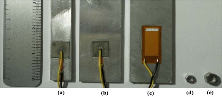 Figura 3.1 - (a) barra estreita e (b) barra larga com a cerâmica de PZT, (c) barra larga com o transdutor MFC, (d) porca de aço pequena e (e) porca grande.