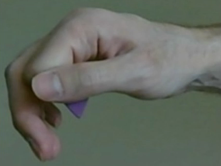 Em seguida, segure a palheta entre o seu dedo polegar e a lateral do seu dedo indicador como na imagem abaixo: Note que a ponta da palheta fica perpendicular, apontando para o corpo da guitarra.