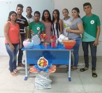 estante feita de canudos de papelão (Figura 01), regadores de canudos de papel, flores de papel, e a réplica de uma planta trepadeira típica da região, tudo produzido com papel reciclado, da