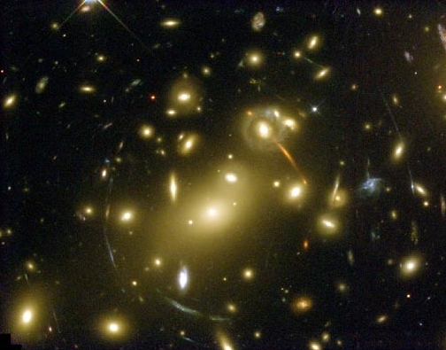 Figura 1.2: Efeitos de lentes gravitacionais no aglomerado de galáxias Abell 2218. A gravidade do aglomerado causa distorções claramente observáveis na imagem das galáxias distantes.