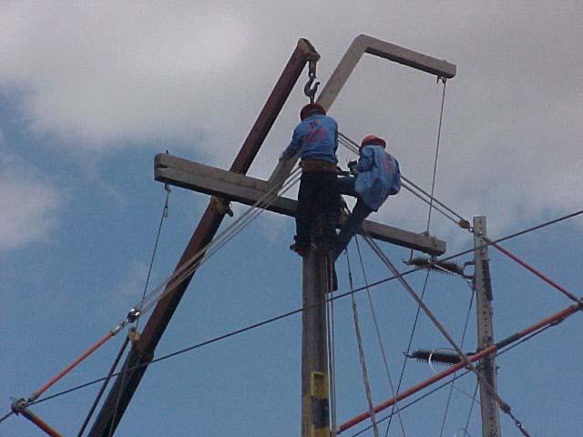 Passo 18 Os eletricistas de topo e de apoio afrouxam os parafusos da cruzeta fixada no poste e