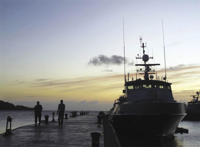 Marinheiros da Guarda Costeira de Trinidad e Tobago passam por um navio de treinamento no cais da estação da Guarda Costeira de Chaguaramas.