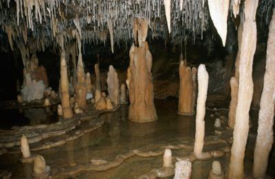 Evidentemente, as estalagmites não surgem simplesmente do chão. A água que pinga da ponta de uma estalactite cai no chão de uma caverna e deposita mais calcita em um monte.
