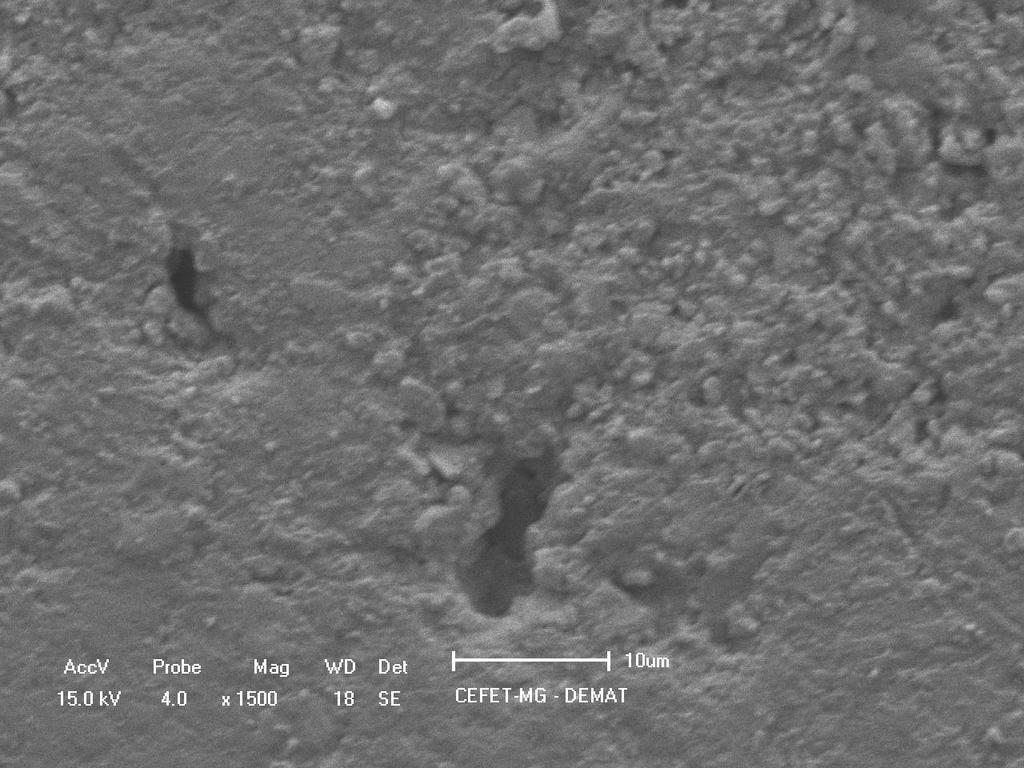 A figura 6 mostra a imagem (MEV) de uma região interna (cortada e polida) da rocha artificial. Pode-se notar a presença de poros micrométricos e uma superfície regular com pouca rugosidade.