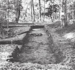 Patrimônio Arqueológico de Caxias do Sul Foto 15: Escavação na Estrutura 26 Casa B ou H. Visão da trincheira Oeste, com as escoras de pedras de um dos esteios no centro. Abril/ Maio de 1967.