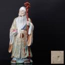 553 :: SHOULAO Escultura em porcelana China, decoração policroma e ouro, representando divindade segurando numa mão pêssego e na outra ceptro com cabeça de
