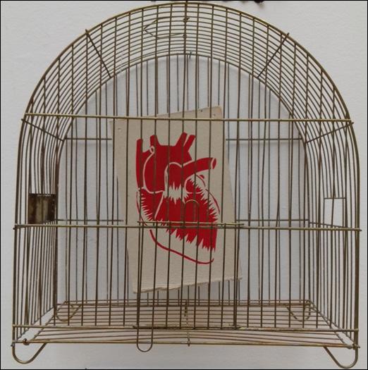 SBEGHEN, M. L. et al. - 168 Fotografia 7 Representação de coração impressa pela técnica de estêncil sobre papel reciclado, dentro de gaiola, intitulado Liberte Vidas.