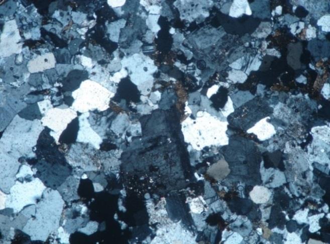 171 potássico é localmente observada; Feldspato potássico: ocorrem como cristais bem formados correspondendo a microclina com geminação cruzada e alguns cristais de ortoclásio com geminação Carlsbad.