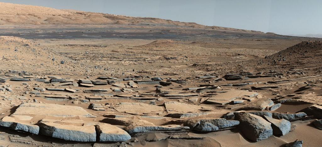 Mars Science Laboratory Rover (Curiosity Rover) Lançamento em 2011 Em primeiro plano, estratos (camadas de rocha) encontrados na base do Monte Sharp, uma montanha de 5 km de