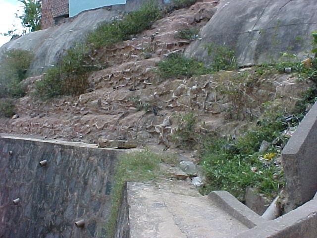 4.12 e 4.13. Figura 4.12: Muro de solo-cimento ensacado no município do Cabo de Santo Agostinho. Obra inacabada. Figura 4.13: Muro de pedra rachão com solo-cimento ensacado no município de Camaragibe.