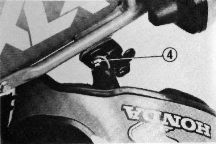 Suporte do Capacete O suporte do capacete (1) está posicionado na lateral esquerda da motocicleta, sob o assento Afaste a tampa da trava (2).