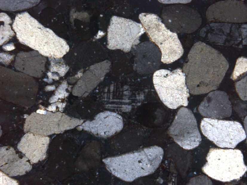 140 microclínio Figura 72. Composição detrítica da rocha sedimentar, mostrando o detalhe no centro do feldspato microclínio. Imagem obtida através de nicóis cruzados.