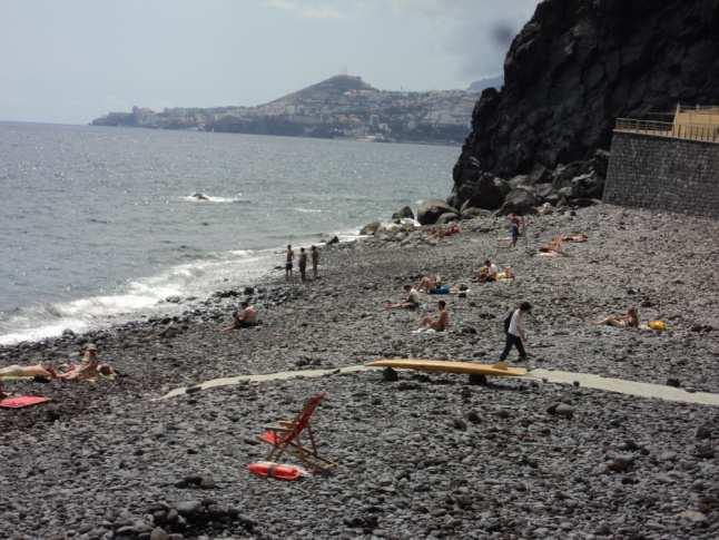 é apelativo - - REGISTO FOTOGRÁFICO Legenda: Ribeira do Faial parque de estacionamento contemplando espaços para veículos para pessoas com mobilidade reduzida ou especial e aspeto geral da praia.