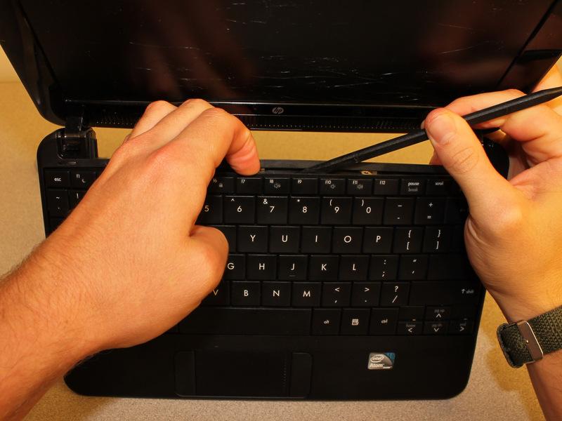 Inserir a extremidade plana do SPUDGER entre meio da borda superior do teclado e da armação de