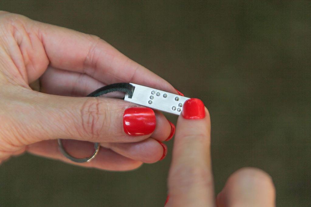 incidunt ut laoreet dolore Chaveiros magna aliquam erat Descrição de imagem: foto de uma mão segurando uma chapa retangular prateada com pontos em braille e em sua extremidade tem um fio de couro com