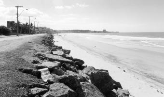 GEOMORFOLOGIA, TIPOLOGIA, VULNERABILIDADE EROSIVA E OCUPAÇÃO URBANA... protegida das ondas provenientes de NE, recebe e mantém os sedimentos trazidos pelas correntes longitudinais provenientes de SW.