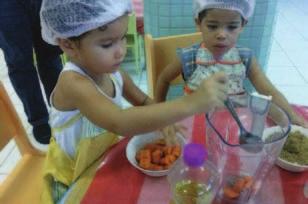 As crianças vão a cozinha participar do processo de preparação dos alimentos, da organização das mesas e da distribuição dos alimentos.