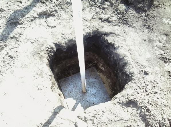 A instalação da placa de recalque é realizada antes das etapas de lançamento dos aterros, na superfície do solo mole, com sua haste visível na superfície do aterro.