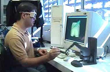 Figura 14 - Pesquisador testando simulador de extração de medula óssea (MACHADO, 2003a) O computador gera imagens tridimensionais na tela, e recebe e envia dados para o dispositivo háptico, que