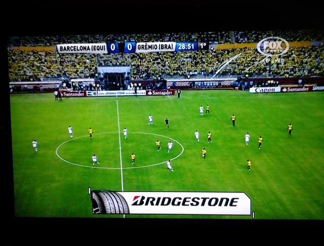 c) marca de pneus anunciada em uma cena de jogo de futebol na televisão brasileira; d) diversas marcas anunciadas em cena de um programa