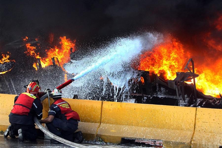 Firemen spray water over a tanker on fire in Caracas on Dec. 29, 2011.