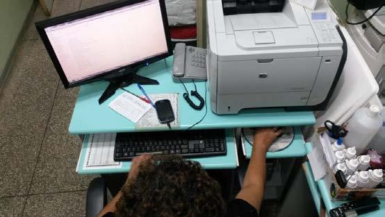 lateralizada com telefone e impressora na mesma superfície impedindo uma boa organização da mesa, onde realiza flexão de ombro direito para