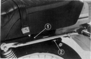 Trava do Assento O assento de sua motocicleta está equipado com duas travas. Para remover o assento, introduza a chave de ignição no suporte do capacete e solte a presilha de segurança (2).