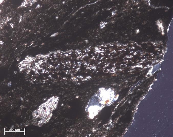 clasto de estaurolite, substituído essencialmente por mica sericítca e óxidos de ferro (em baixo) e a matriz envolvente (em cima).