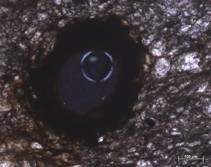 139 Microscopia de luz transmitida Aspeto pormenorizado de um vazio rodeado por óxidos