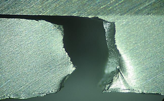 Nesta superfície de fratura é visível uma camada estriada da liga de alumínio soldada ao