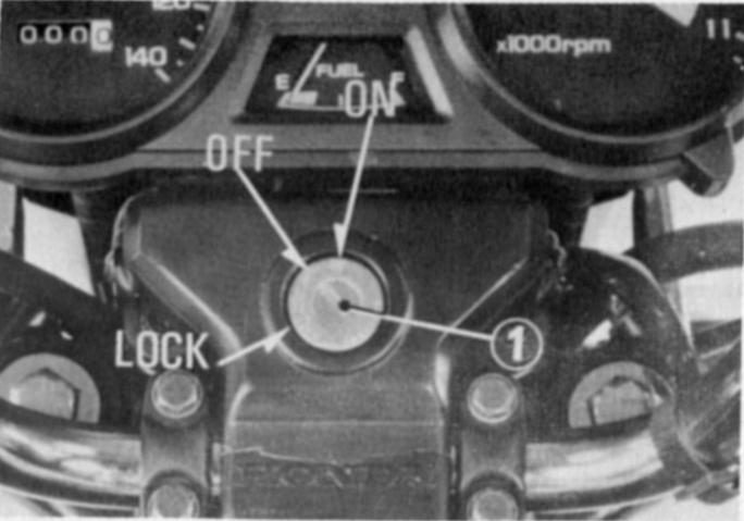 Interruptor de ignição O interruptor de ignição (1) está posicionado abaixo do painel de instrumentos. Posição da chave Função Condição da chave LOCK Travamento do guidão.