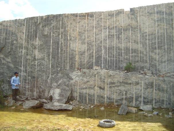 Foto 3.4 (A) Afloramento de CHO em pedreira com a rocha apresentando feições migmatíticas (tons claros), no meio da rocha com coloração cinza-azulada.