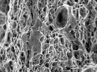 4.4.3, mostra a presença também de facetas de clivagem, indicando uma fratura mista e, em detalhe, um dimple de maior tamanho, indicando um possível