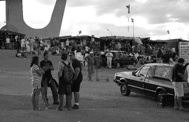 Pessoas na feira e sentadas no gramado,