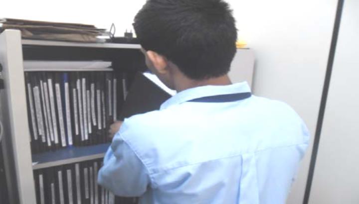 estruturas da coluna cervical. Observa-se membros superiores inserindo pastas em área de curto alcance inserindo documentos em armário.