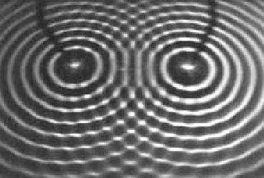 b) c) d) Questão 13 (Unesp 2009) A figura mostra um fenômeno ondulatório produzido em um dispositivo de demonstração chamado tanque de ondas, que neste caso são geradas por dois martelinhos que
