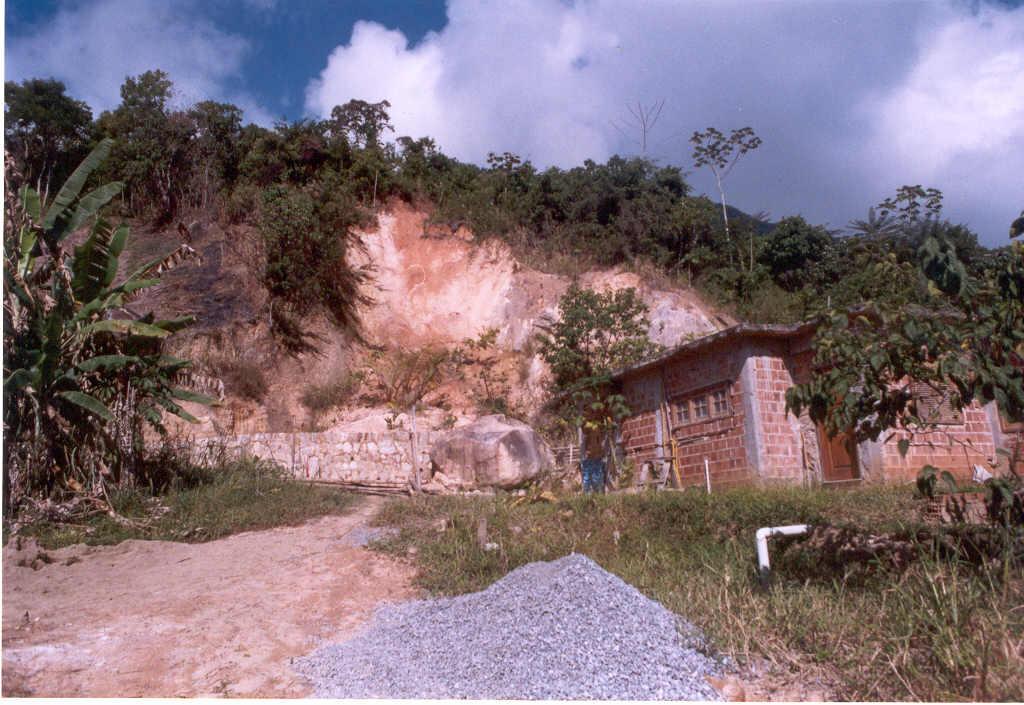 Foto II-28 Estrada de acesso a Parati- Mirim. Edificação em base de morro com instabilização da encosta e queda de matacão, caracterizando uma área de risco.