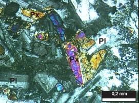 b) Descrição microscópica: a principal textura é porfirítica, caracterizada pela presença de fenocristais de plagioclásio e clinopiroxênio, prismáticos e euédricos, com dimensões variáveis entre 1 a