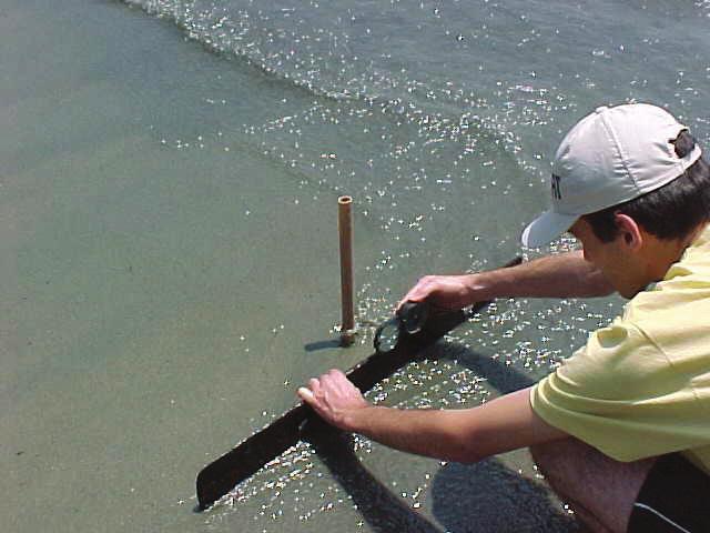 Figura 4.8.2.2-4. Leitura da declividade da praia na linha d água (limite inferior do estirâncio) com auxílio de bússola geológica do tipo Brunton.