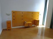 madeira, uma secretária em madeira, um banco em madeira, um televisor da marca Grundig, três candeeiros de parede, um par de cortinados.