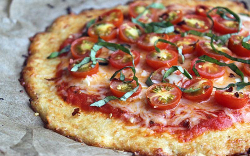 PIZZA DE COUVE FLOR 1 xícara couve-flor ralada 1 xícara queijo mussarela ralado Ovo Sal Orégano Mussarela a gosto 1 tomate em rodelas Manjericão Rale bem a couve-flor e coloque em uma xícara.